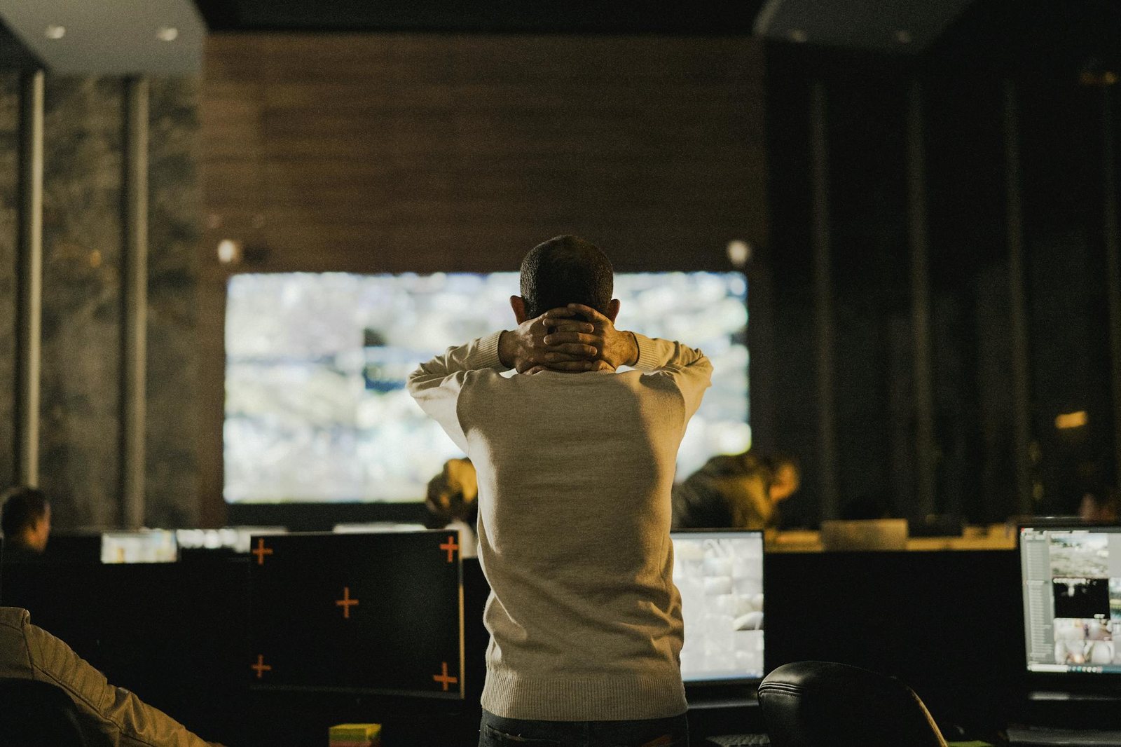 Operator standing in a control room with screens.